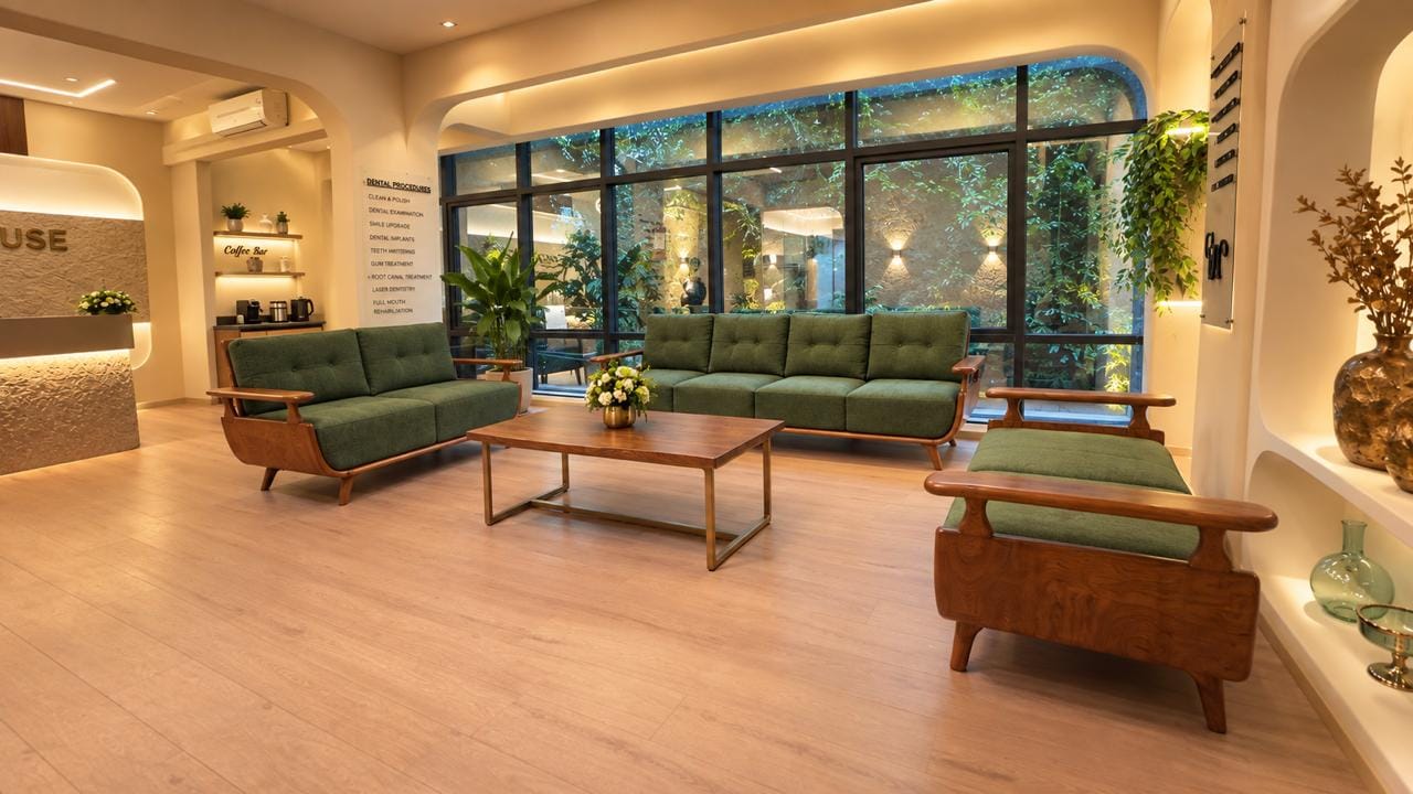 Waiting lounge: green sofas beside a wall of garden-facing windows