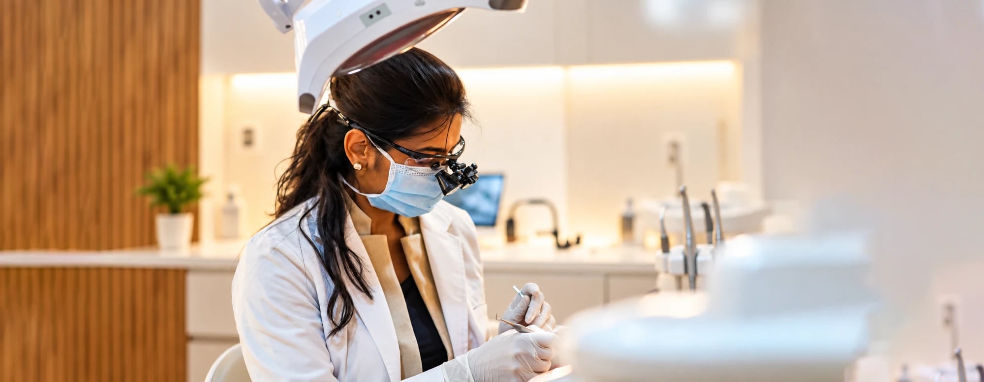 A dentist at The Root Cause, wearing magnifying loupes, treating a patient in the clinic